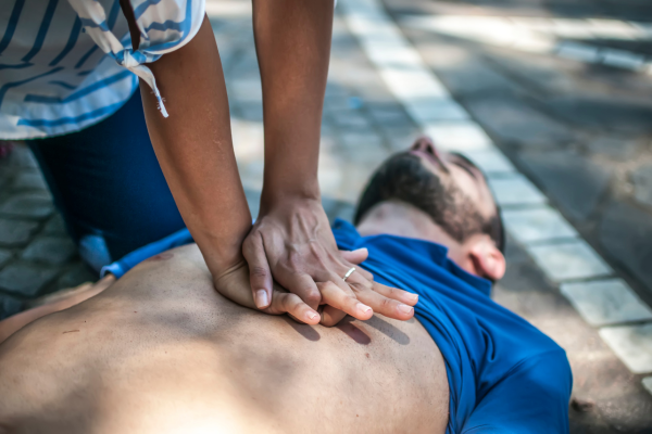 Woman performing CPR first aid on unconscious man on the ground