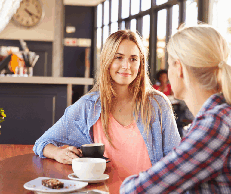 two female friends having a conversation over coffee in a cafe