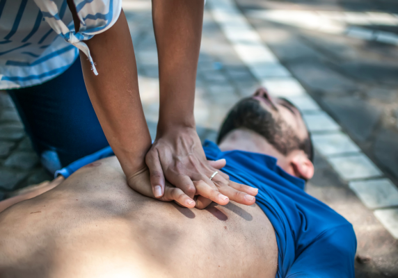 Woman performing CPR first aid on unconscious man on the ground