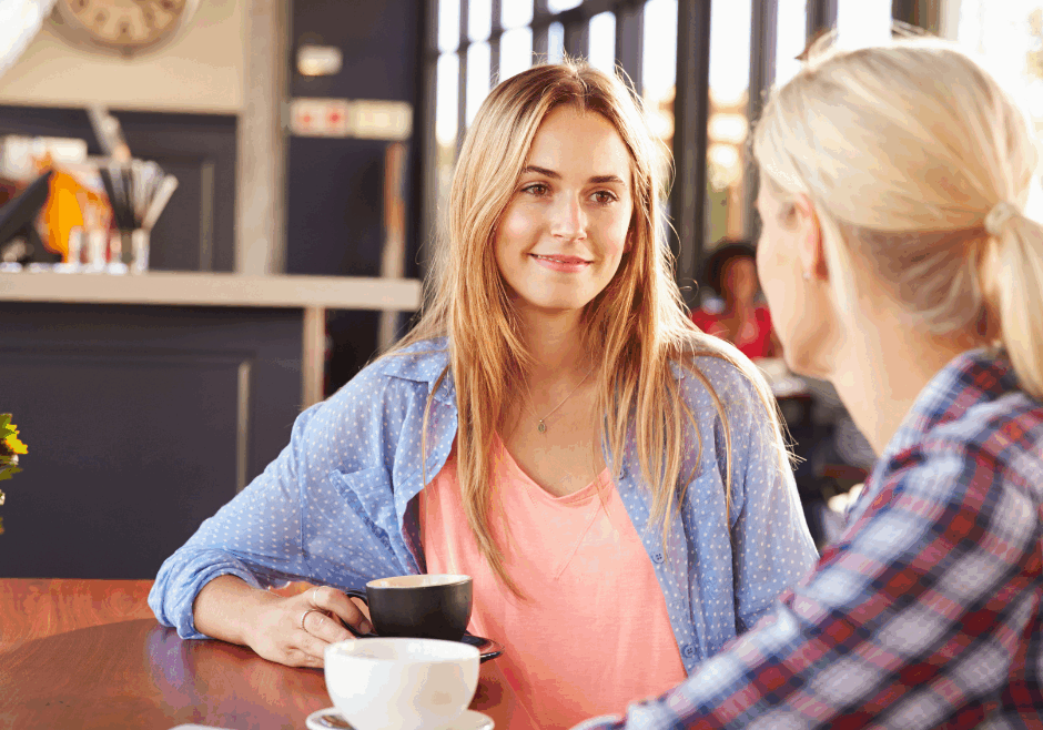 two female friends having a conversation over coffee in a cafe