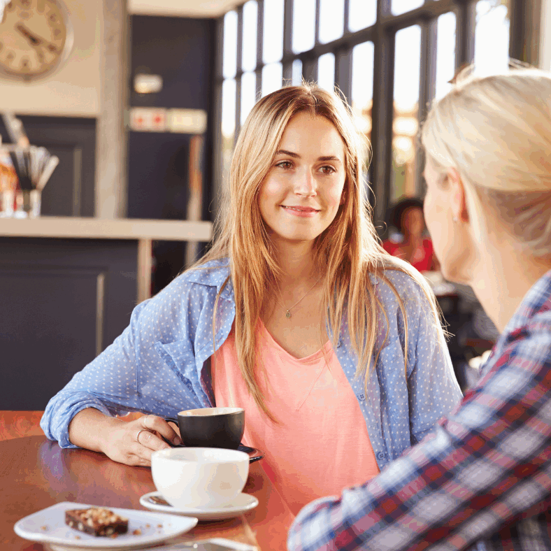 two female friends having a conversation over coffee in a cafe